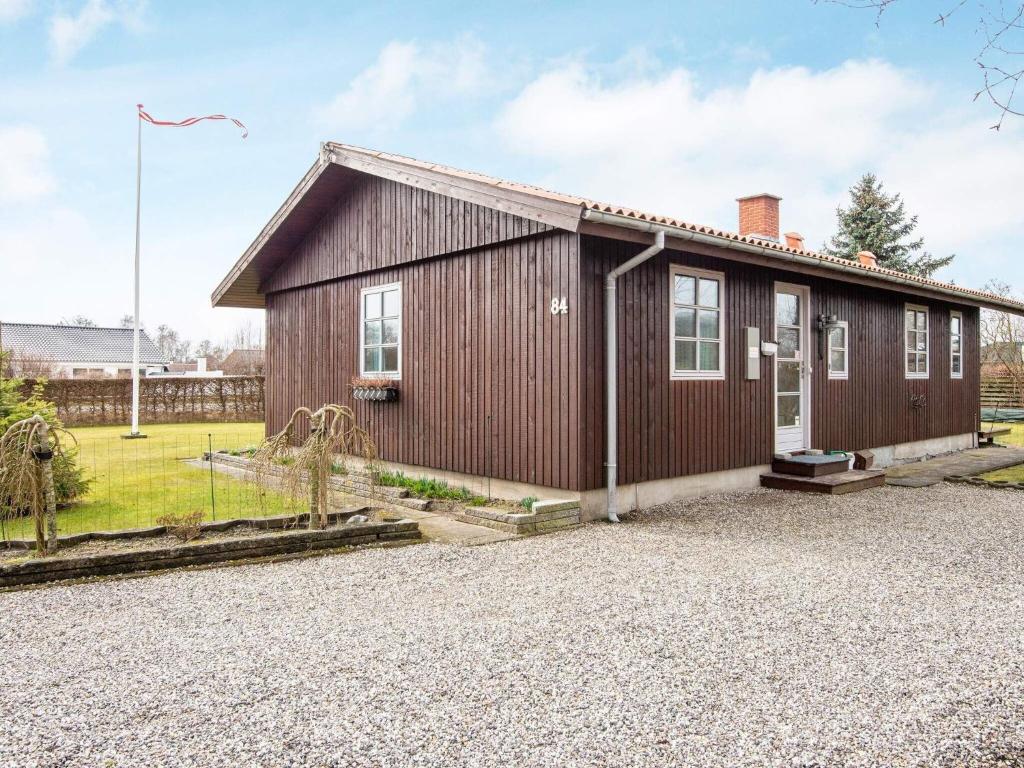 un pequeño edificio de madera con entrada de grava en 9 person holiday home in Grenaa en Grenå