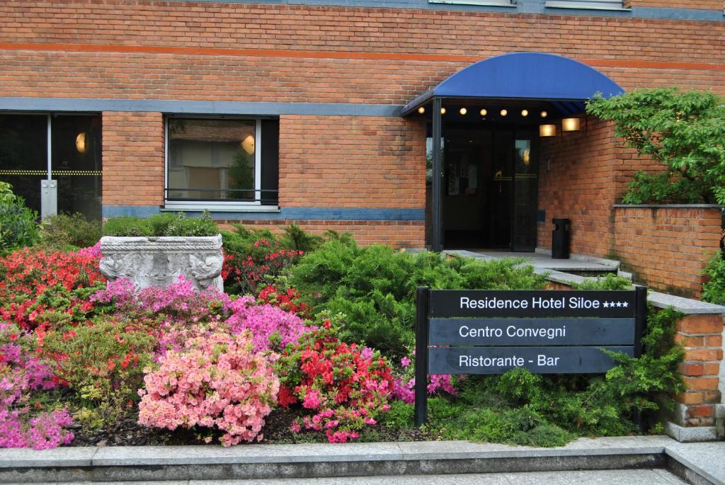 a sign in front of a building with flowers at Residence Hotel Siloe in Milan