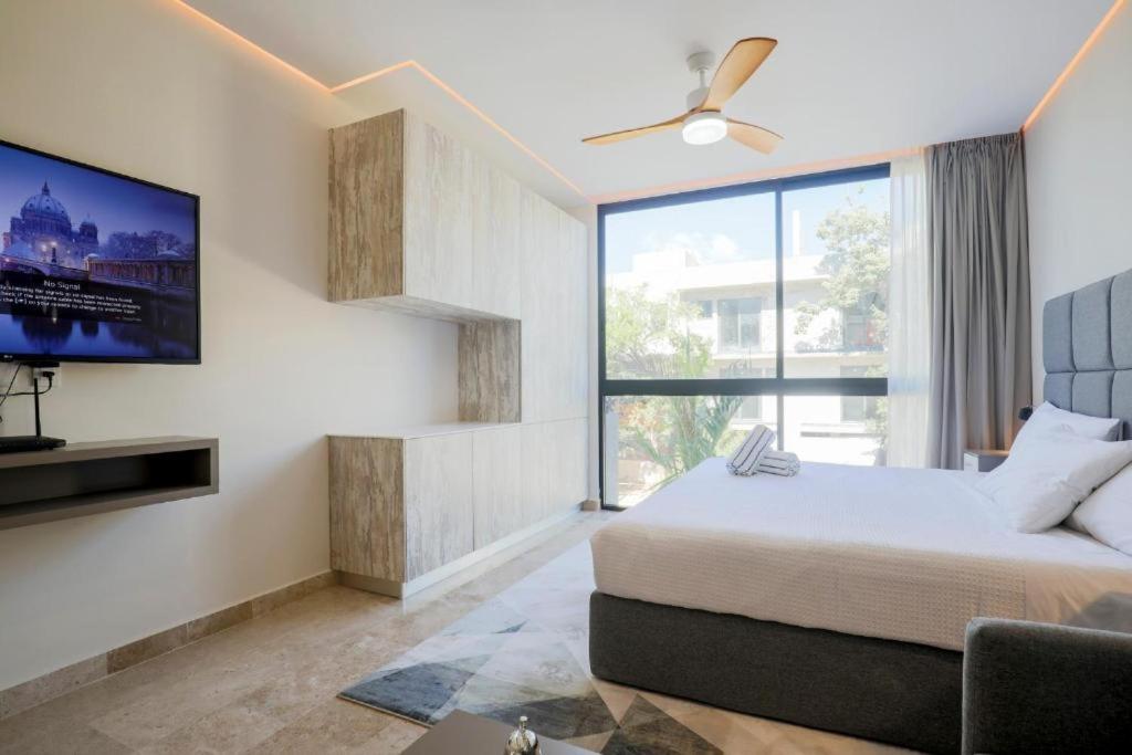 a bedroom with a bed and a flat screen tv at Apartamento Aldea Zama 7 in Tulum