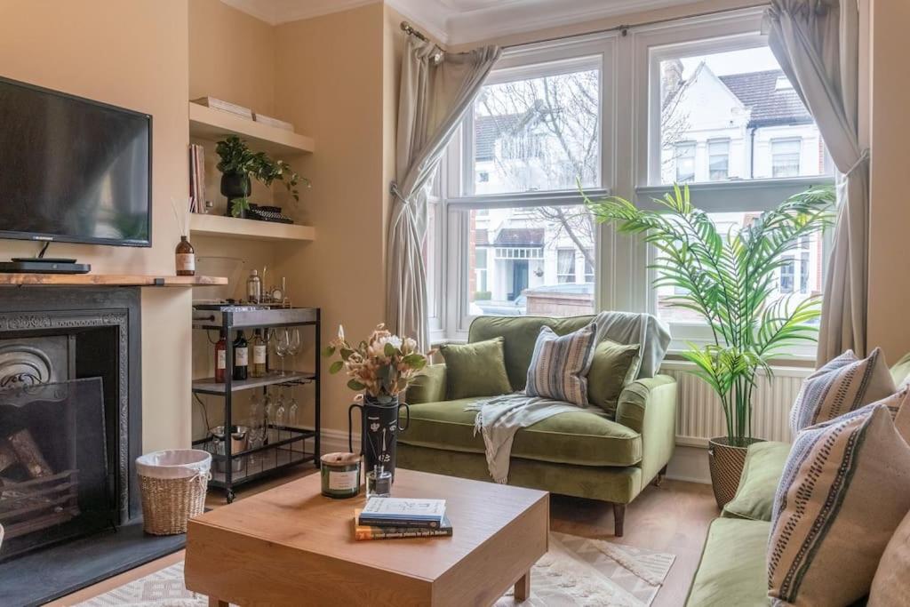 ein Wohnzimmer mit einer grünen Couch und einem Kamin in der Unterkunft Dahomey Home - Streatham - London in London