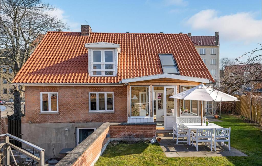 uma casa com um telhado laranja e uma mesa com um guarda-chuva em Nice Home In Dyssegrd With Wifi And 5 Bedrooms em Søborg