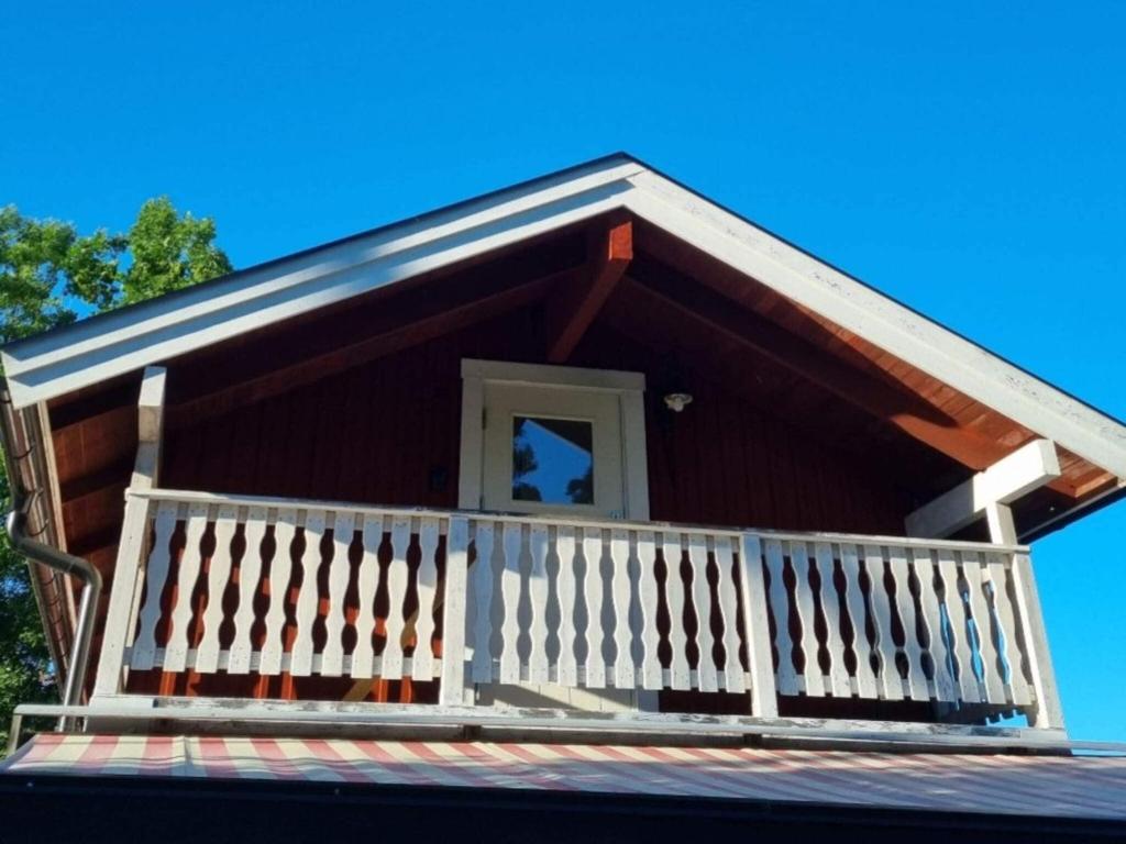 ein Holzhaus mit weißem Geländer und einer Veranda in der Unterkunft Holiday home GRISSLEHAMN XII in Grisslehamn