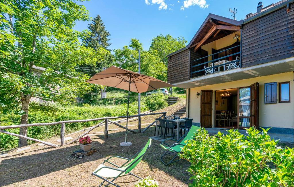 a patio with chairs and an umbrella in front of a house at 2 Bedroom Awesome Home In Careggine in Careggine