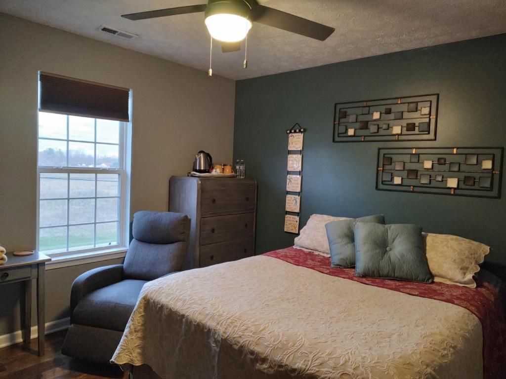 una camera con letto, sedia e ventilatore a soffitto di Indys Hidden Gem a Indianapolis