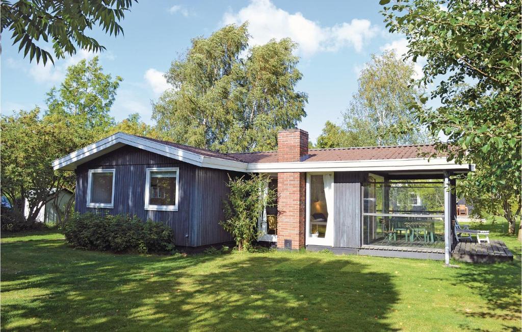 ein kleines Haus auf einem Feld mit einem Rasenplatz in der Unterkunft 3 Bedroom Pet Friendly Home In Dronningmlle in Dronningmølle