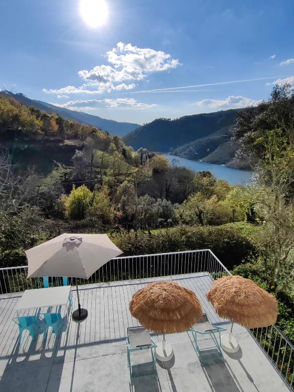 two umbrellas and chairs on a patio with a view at Vale Da Misarela in Geres