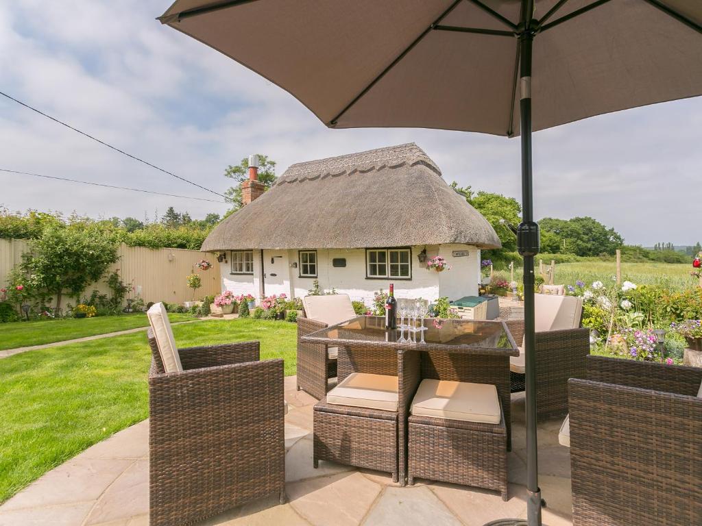 a patio with a table and chairs and an umbrella at Brittons Hill Cottage in Wavehorne
