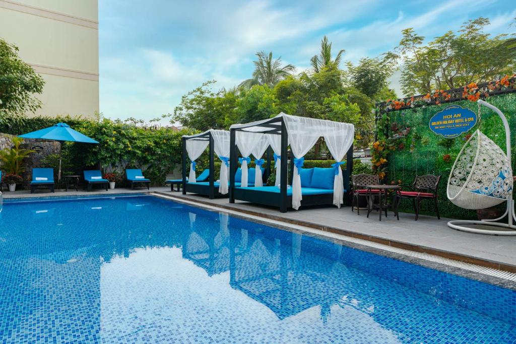 uma piscina com cadeiras, uma mesa e uma tenda em Hoi An Golden Holiday Hotel & Spa em Hoi An