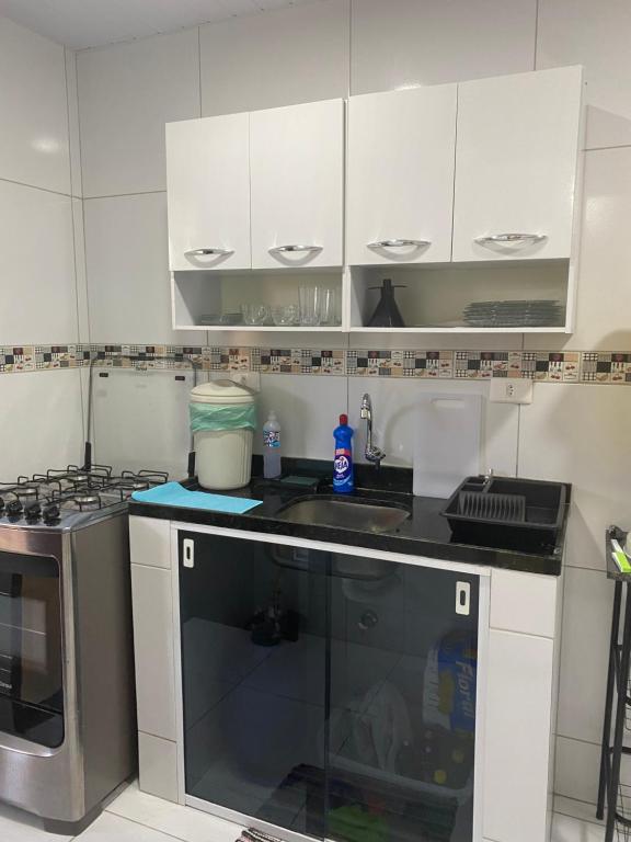a kitchen with white cabinets and a sink at Cantinho da Dhéia 03 in Porto De Galinhas