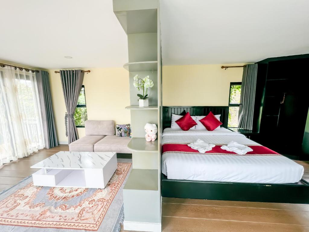 a bedroom with a bed with red pillows and a couch at HaiVen Farm Homestay in Phumĭ Khŭn Réam