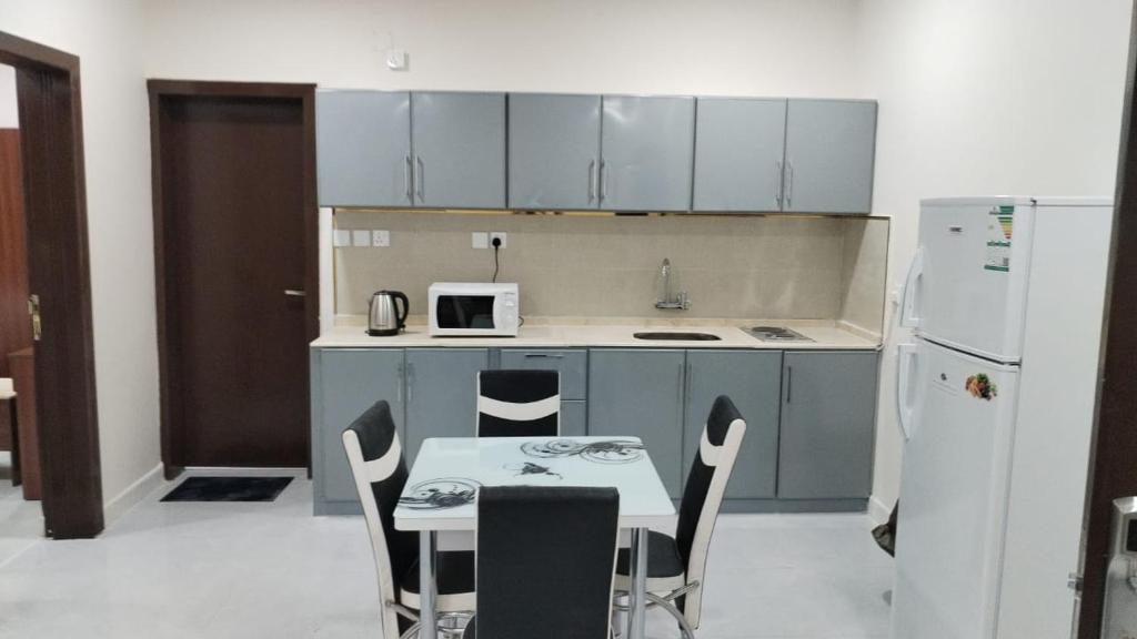 La cuisine est équipée d'une table, de chaises et d'un réfrigérateur. dans l'établissement هوتيل نجران للشقق الفندقية, à Najran