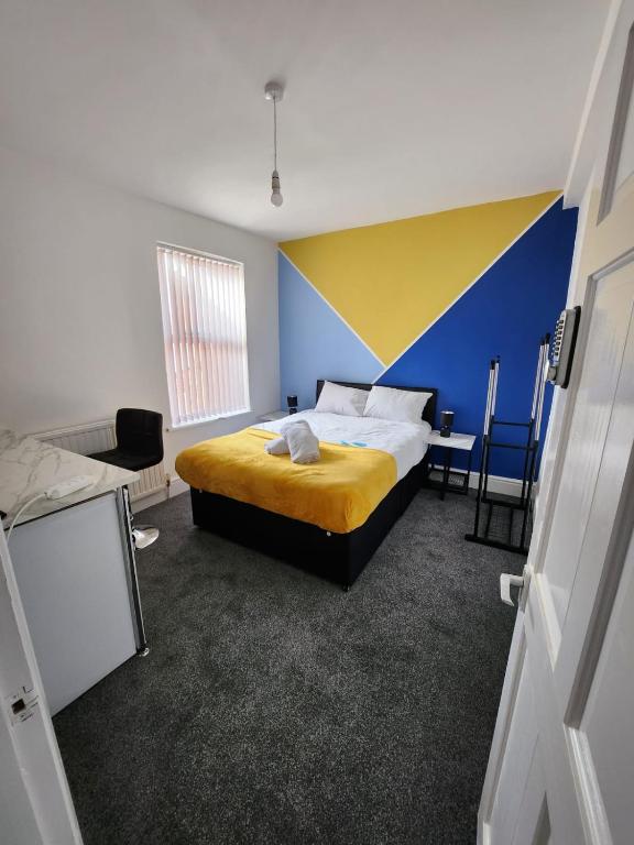 - une chambre avec un lit et un mur bleu et jaune dans l'établissement Bamville Shared House, à Birmingham