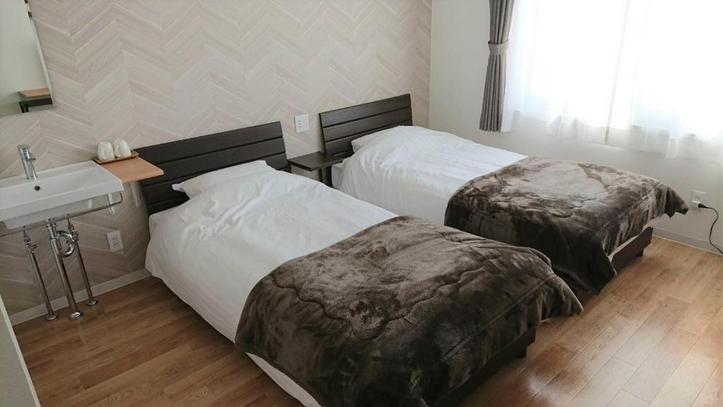 ein Hotelzimmer mit 2 Betten und einem Waschbecken in der Unterkunft Sarabetsu-mura chiiki Kouryu Center - Vacation STAY 21683v in Naka-satsunai