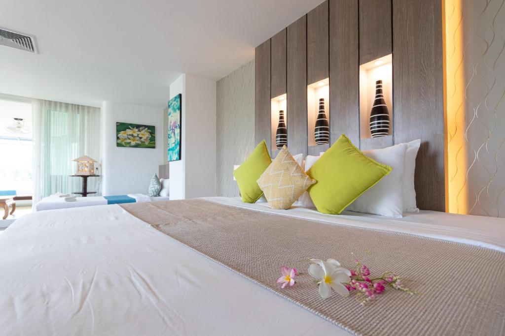 ein Schlafzimmer mit einem großen Bett mit grünen und weißen Kissen in der Unterkunft Aochalong Villa Resort & Spa - SHA Plus in Chalong 