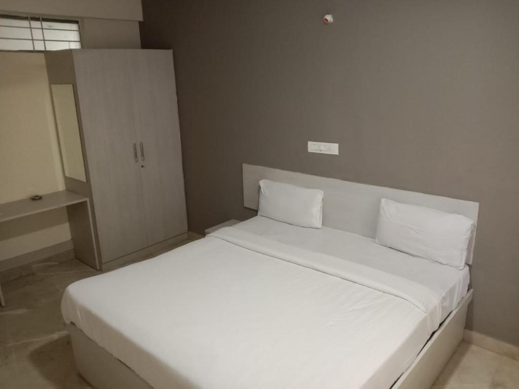 班加羅爾的住宿－PRIDE MANYATA，卧室内的一张带两个枕头的白色床