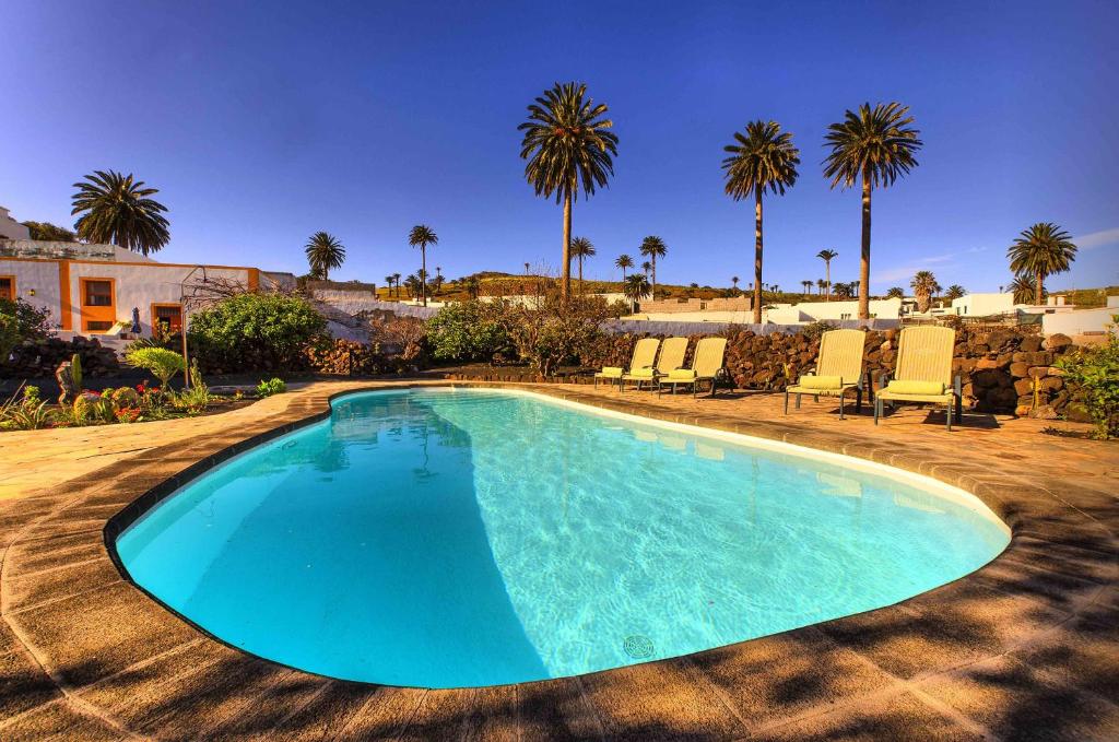 - une piscine bordée de chaises et de palmiers dans l'établissement Casa Rural Villa Lola Y Juan, à Haría