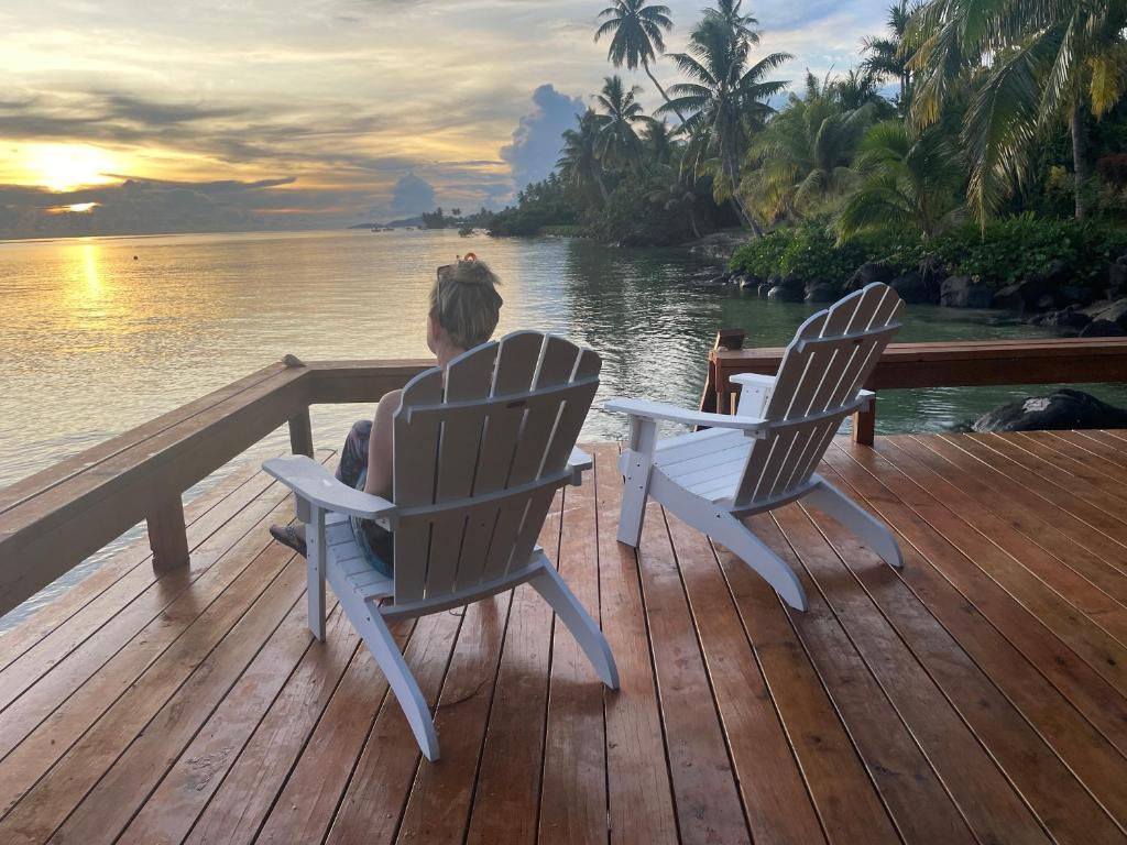 a person sitting in chairs on a deck overlooking the water at Vale Sekoula, Private Villa on the Ocean with Pool in Matei