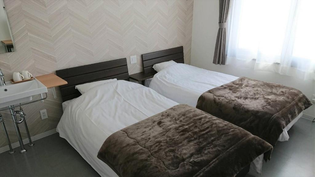 um quarto de hotel com duas camas e um lavatório em Sarabetsu-mura chiiki Kouryu Center - Vacation STAY 25699v em Sarabetsu
