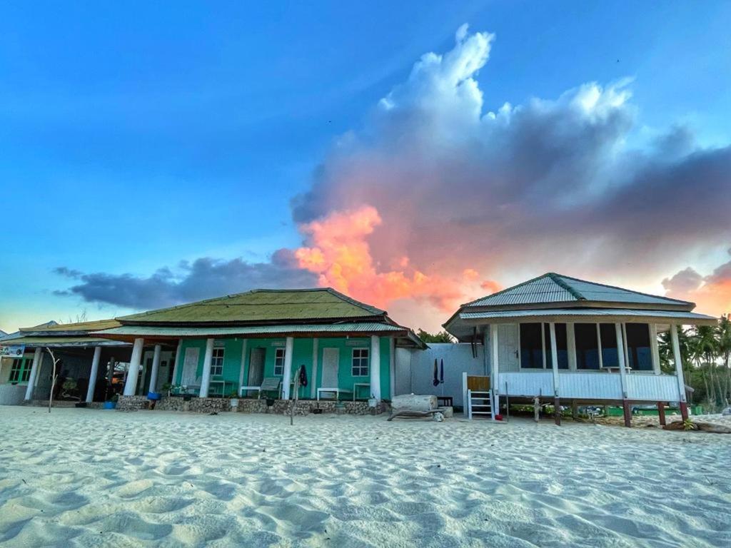 two houses on the beach with a fire in the background at Home Stay Ramli in Bira