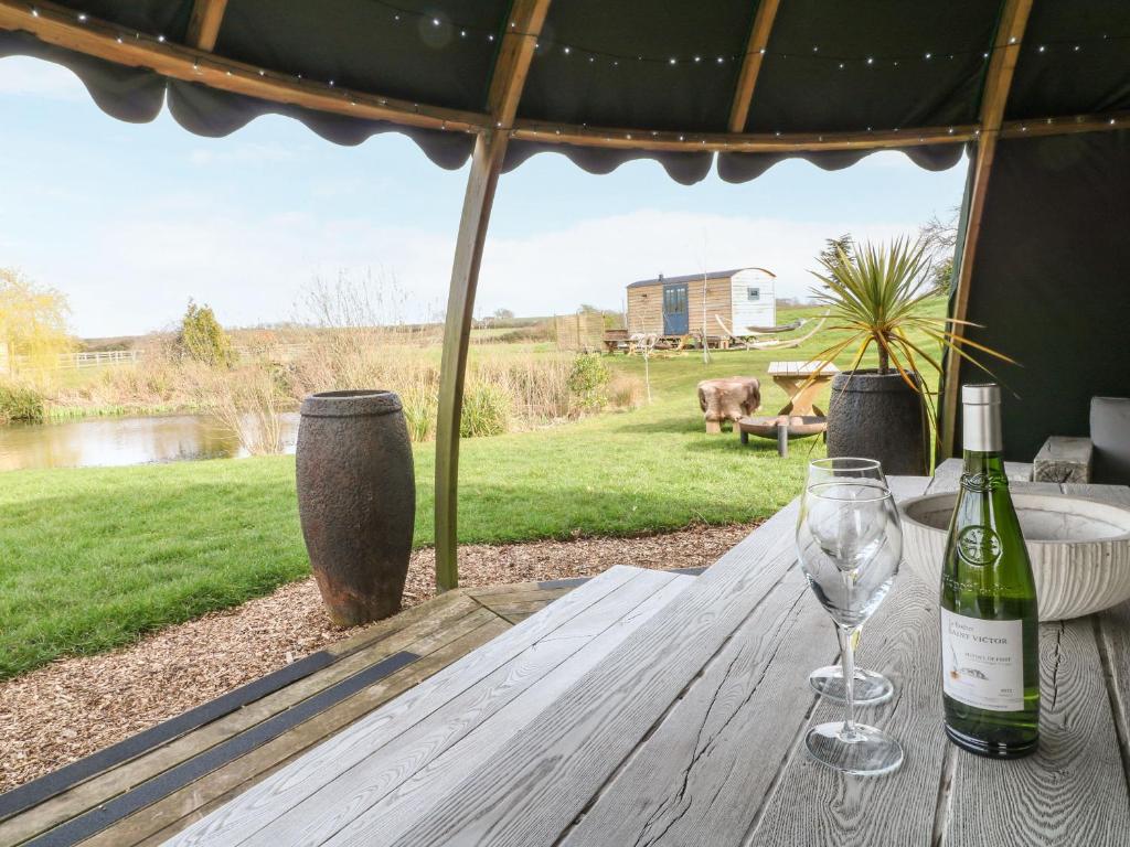 a wooden table with a bottle of wine and a glass at Lillie's Shepherds Hut in Nottingham