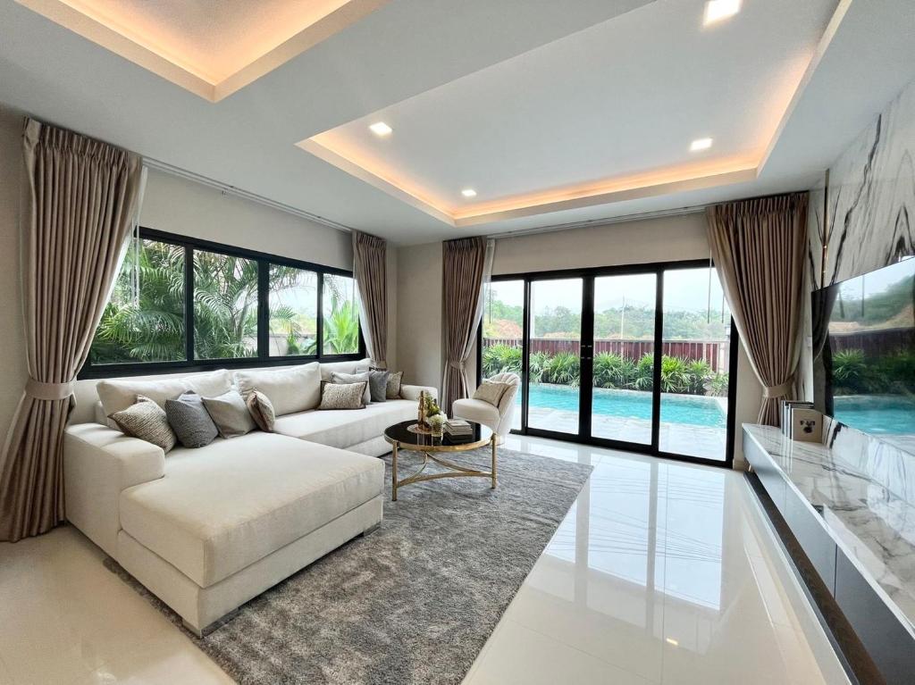 ein Wohnzimmer mit einem weißen Sofa und großen Fenstern in der Unterkunft Southern Peak Pool Villa Huay Yai Pattaya in Ban Huai Yai