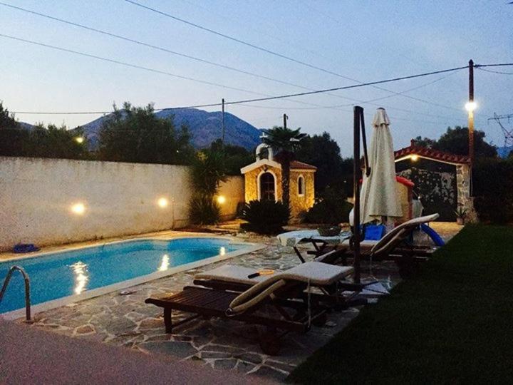 a swimming pool with chairs and an umbrella next to a house at DIMIS swimming pool small villa in Eretria