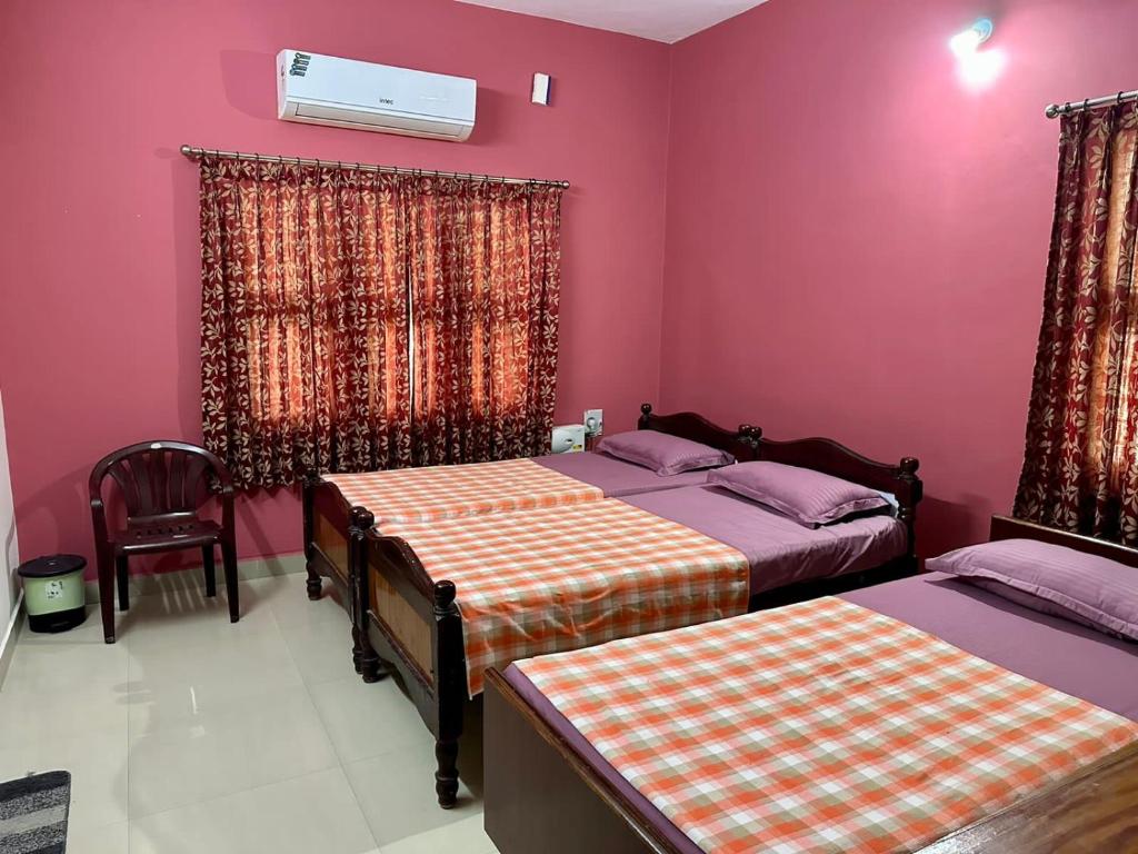 a bedroom with two beds and a pink wall at Chidambaram Spiritual Stay in Chidambaram