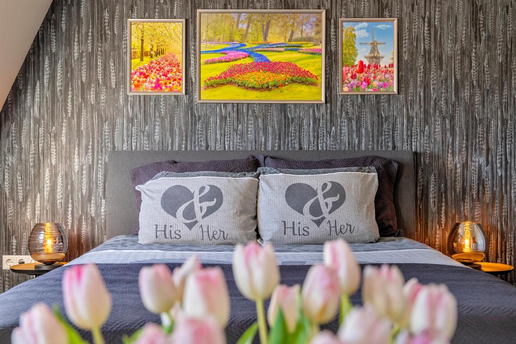 een slaapkamer met een bed met vier schilderijen aan de muur bij Liv Inn in Hillegom
