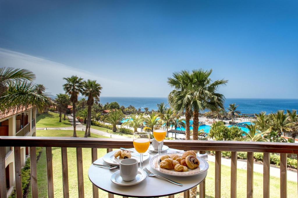 einen Tisch mit Speisen und Getränken auf einem Balkon mit Meerblick in der Unterkunft Esencia de La Palma by Princess - Adults Only in Fuencaliente de la Palma