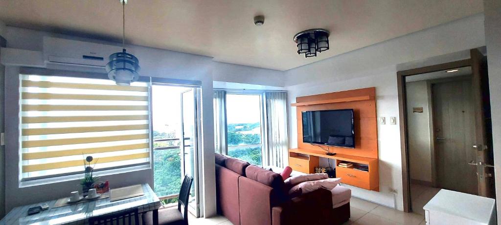 a living room with a couch and a television at De Luxe, Standard and Studio Suites -The Breeze Residences-close to Airport,Mall of Asia, US Embassy in Manila