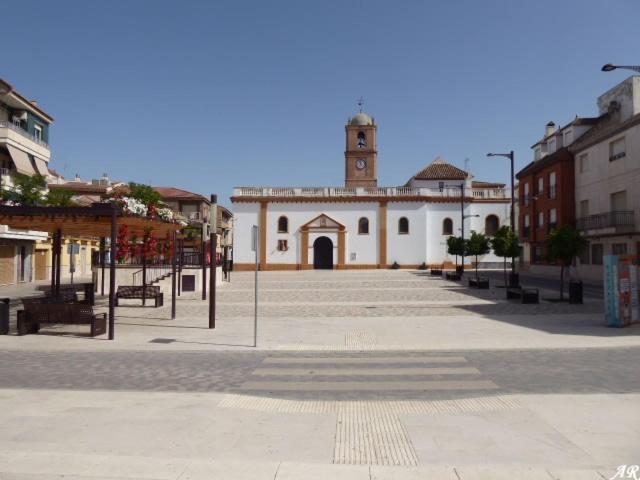 a building with a clock tower in the middle of a street at APARTAMENTO ANCHA CENTRO in Huétor-Tájar