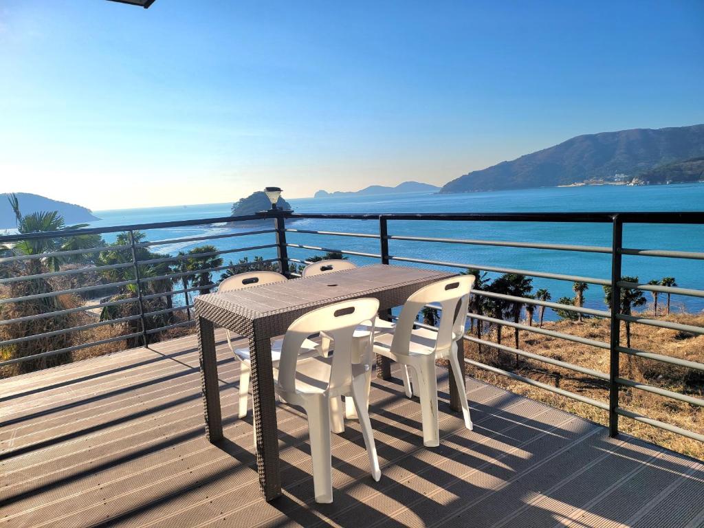 una mesa y 2 sillas en una terraza con vistas al agua en oneday in geoje, en Geoje