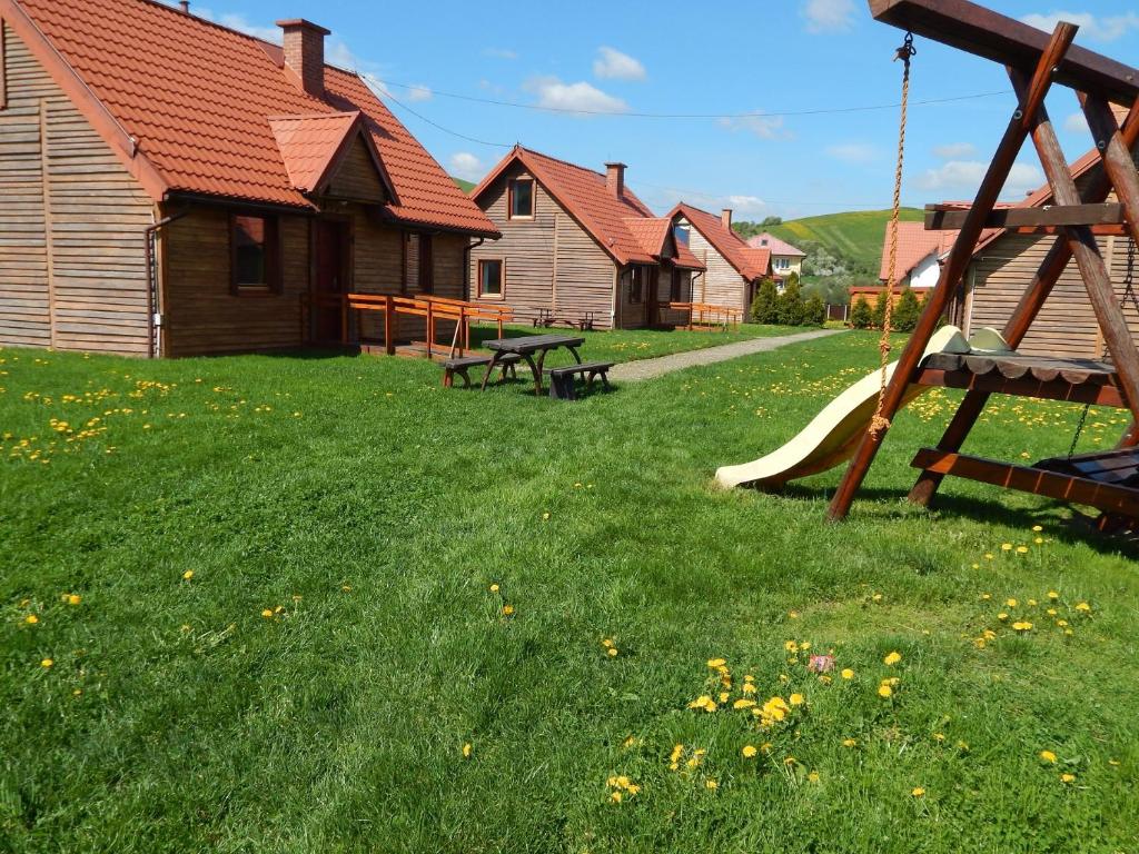 a playground with a slide in a yard with houses at Caloroczne Domki w Gorach"ALEKSANDER" in Kacwin