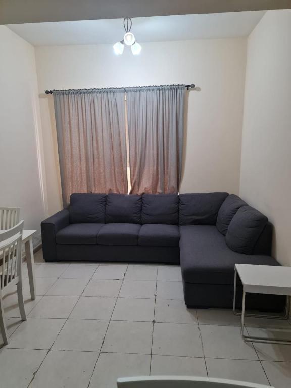 a living room with a blue couch in front of a window at Almond Tower A5 in Ajman 