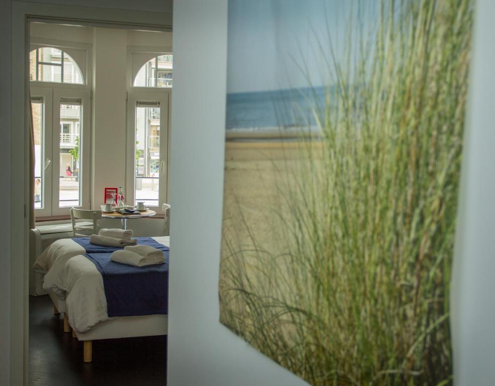 a bedroom with a bed and a view of the beach at Hotel Aan Zee in De Panne
