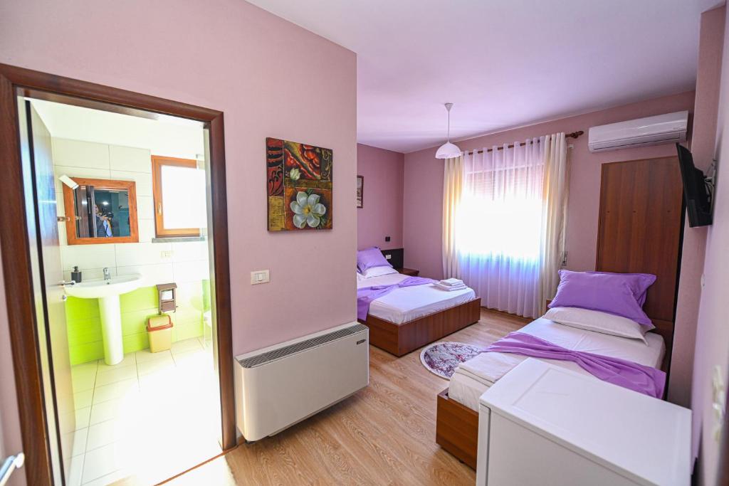 a bedroom with two beds and a sink and a mirror at Hotel Epoka in Shkodër
