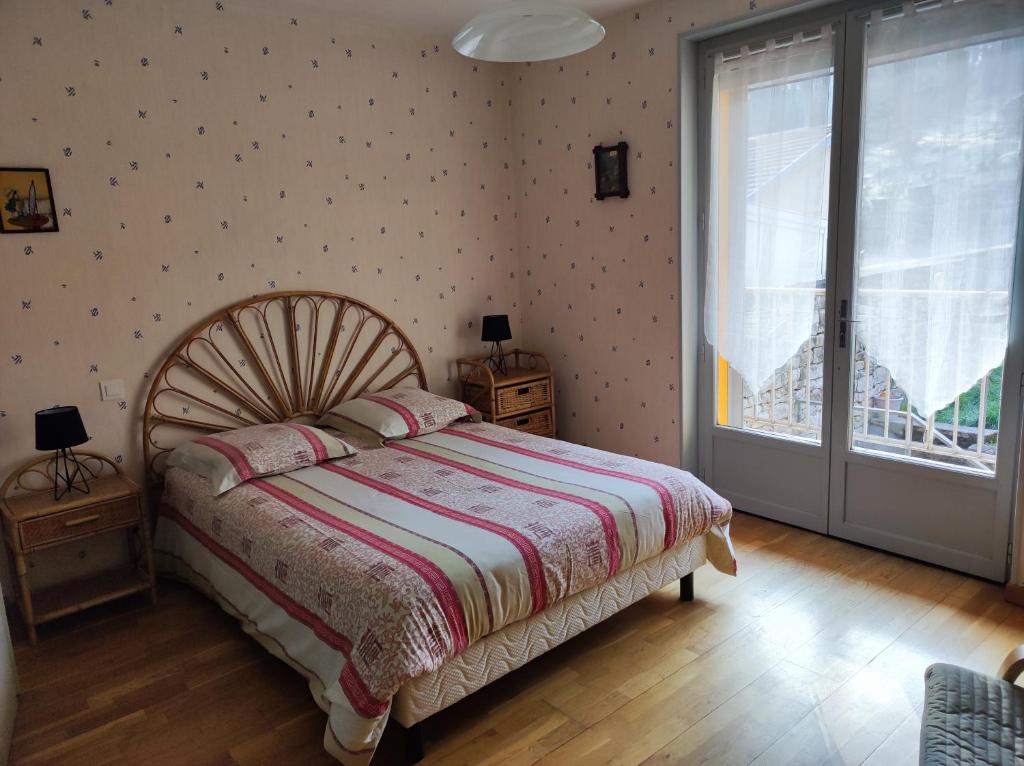 a bedroom with a bed and a large window at Résidence L'Alexandra 2 étoiles in Bourbonne-les-Bains