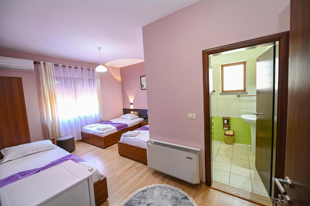 a room with two beds and a bathroom with a shower at Hotel Epoka in Shkodër
