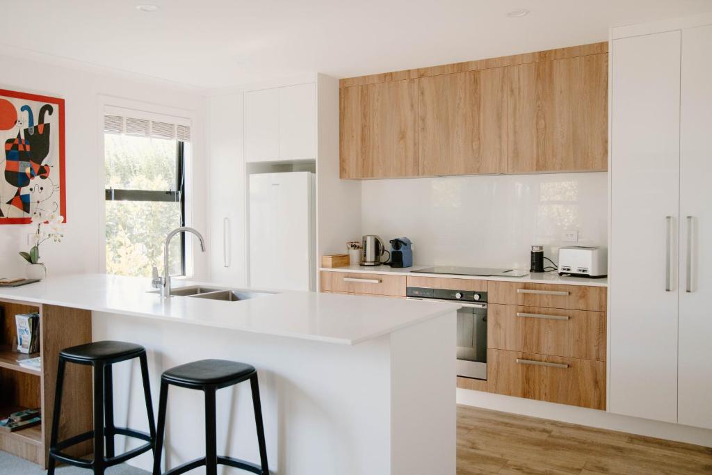 a kitchen with a white counter and two black stools at Nelson Central Town House in Nelson