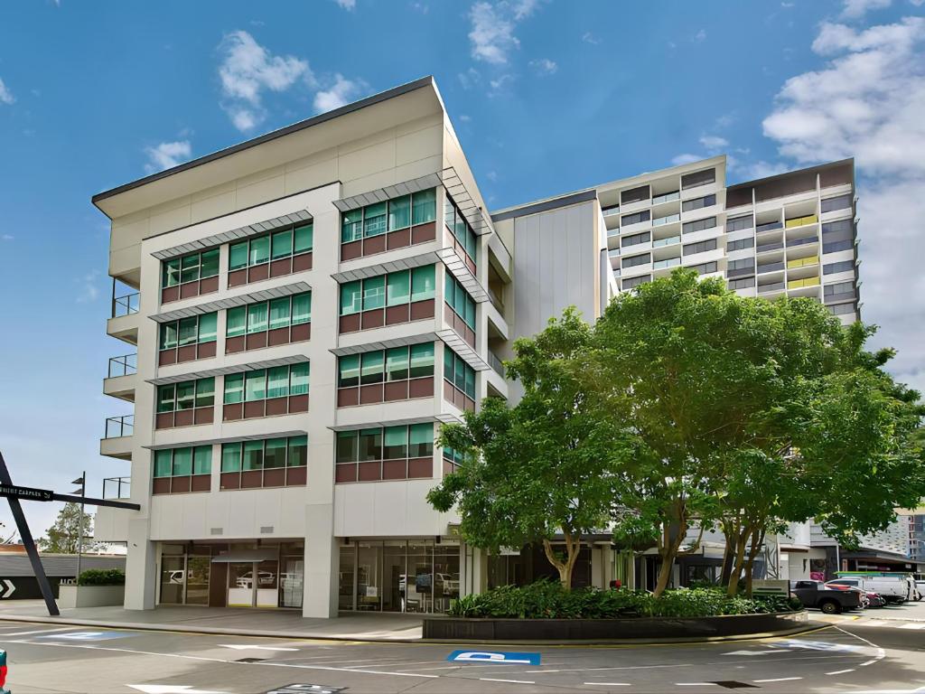 um edifício de escritórios com uma árvore em frente em Link Portside Wharf Apartment Hotel em Brisbane
