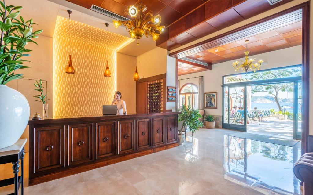 a woman standing at the reception desk of a hotel lobby at Hotel Cala Fornells in Paguera