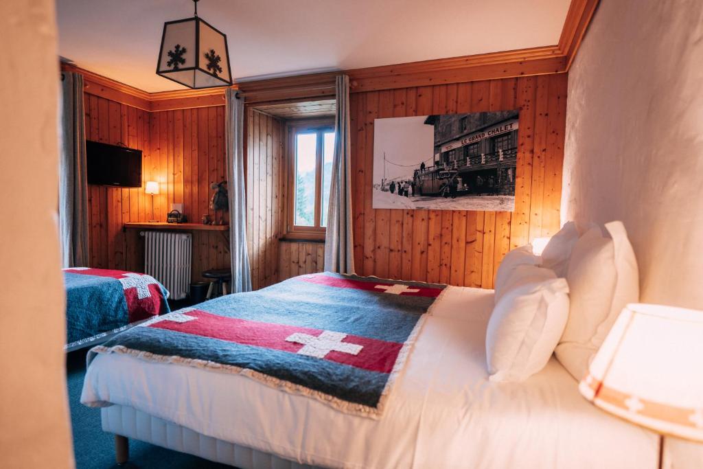 a bedroom with a bed with a cross blanket on it at Chalet-hôtel Gai Soleil in Les Contamines-Montjoie