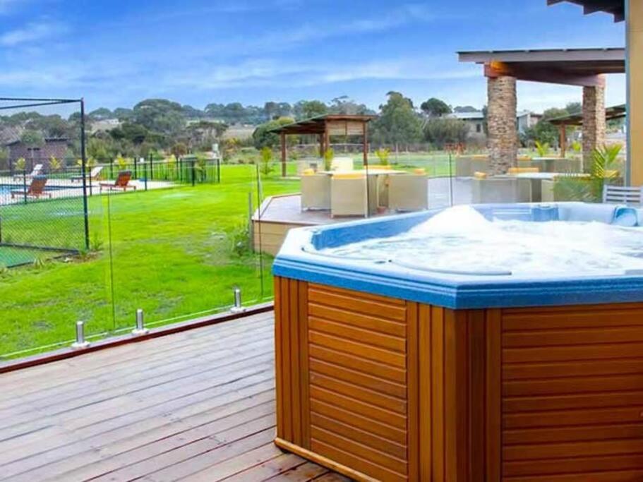 a hot tub on a deck with a view of a yard at 241 - Modern Exclusive Resort Villa w Pool Spa & Gym in Cowes