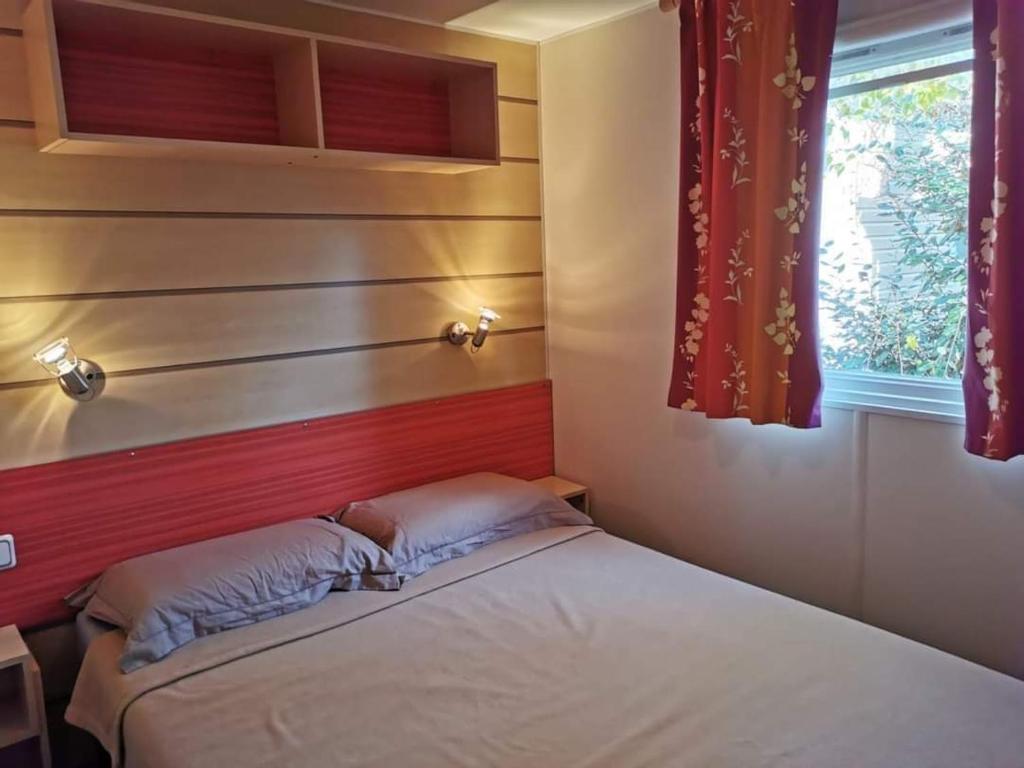um pequeno quarto com uma cama e uma janela em Bungalow des amis em Le Grau-du-Roi