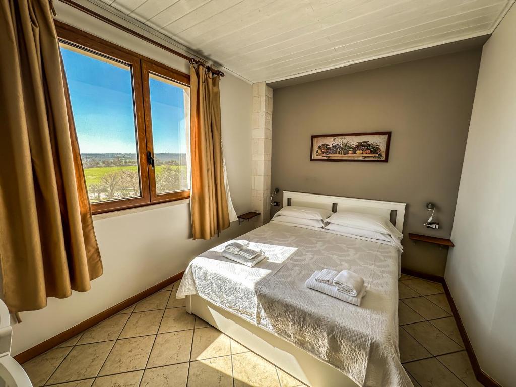 una camera da letto con un letto e una grande finestra di B&B Il Leccio ad Alberobello