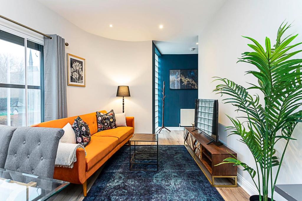a living room with an orange couch and a plant at Gorgeous Roehampton Flat in London