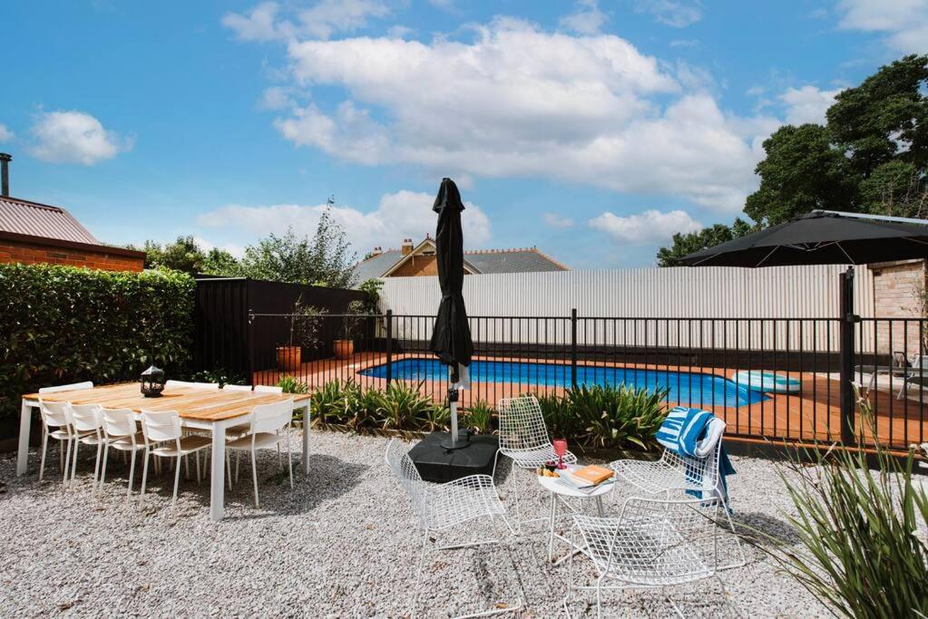 a patio with a table and chairs and a pool at 'Mortimer Gardens' Country Charm in the Heart of Mudgee in Mudgee