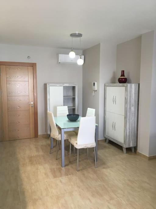 een eetkamer met een tafel en witte stoelen bij Apartamento nuevo en pleno centro. in Carboneras