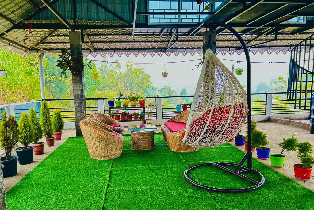 a patio with green grass and hammocks and potted plants at Mirik Homestay in Mirik