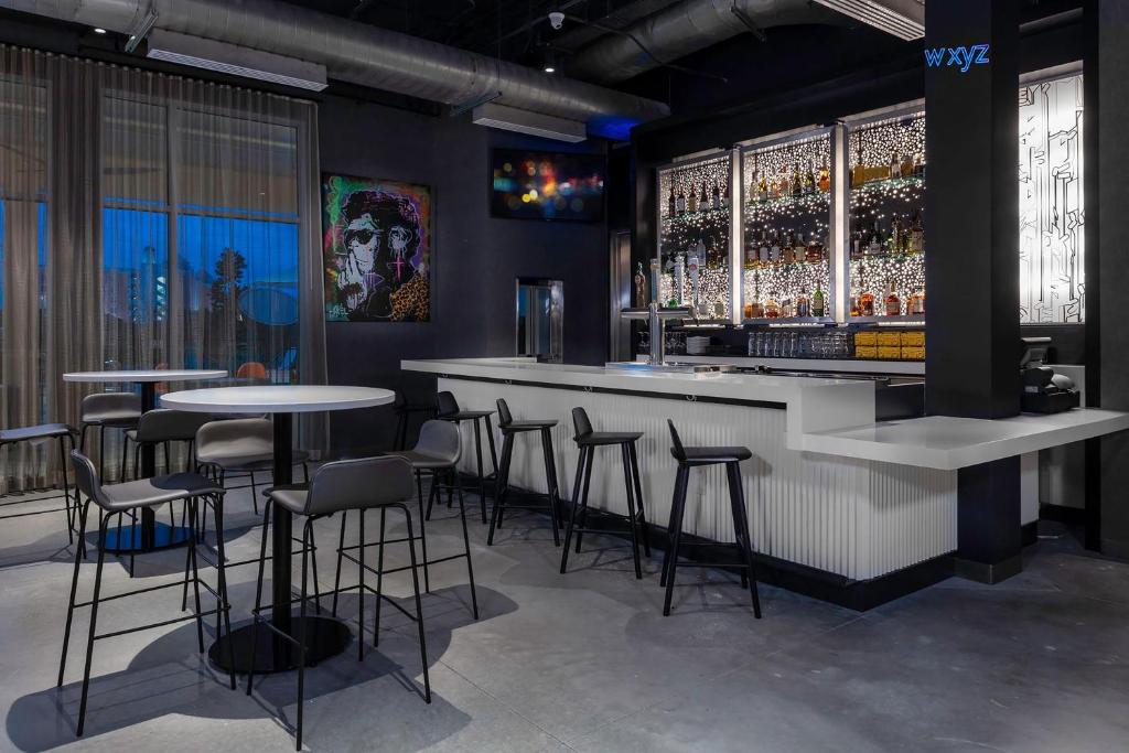a bar with stools and tables in a room at Aloft Orlando Lake Buena Vista in Orlando